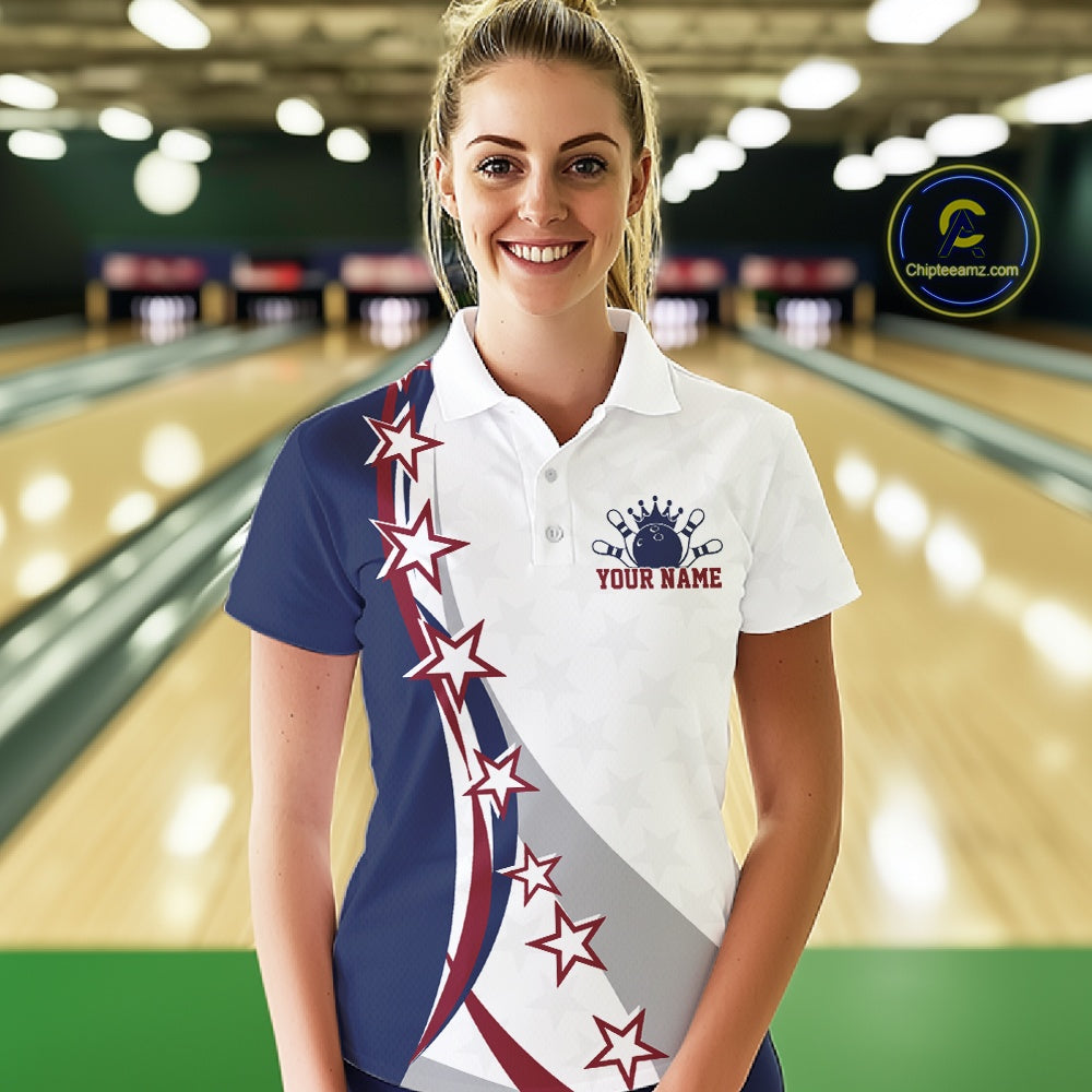 Front view of a female model in a bowling lane wearing a red, white, and blue polo shirt with bowling artwork, sweeping stars, and stripes.