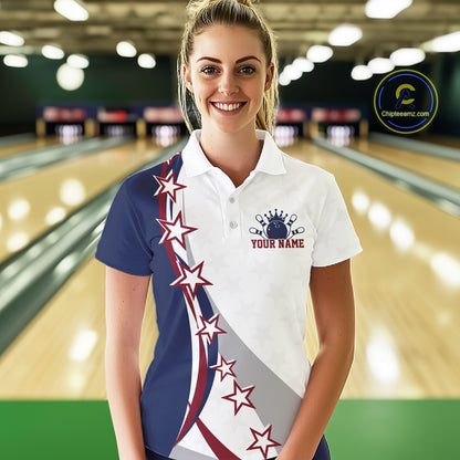 Front view of a female model in a bowling lane wearing a red, white, and blue polo shirt with bowling artwork, sweeping stars, and stripes.
