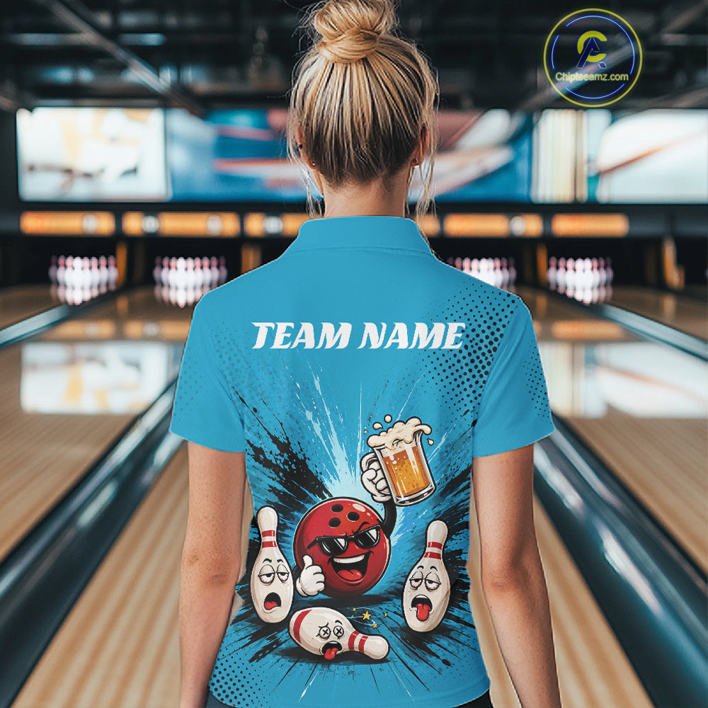 A woman viewed from behind wearing a bright blue bowling-themed short-sleeve polo shirt with a large cartoon bowling graphic and the text 'TEAM NAME' on the back. The background shows a blurred bowling alley interior with lanes and pins.