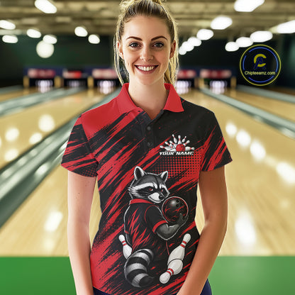 A woman stands in a bowling alley wearing a short-sleeve polo shirt with a red and black brushstroke design, a raccoon holding a bowling ball graphic, and a white 'YOUR NAME' placeholder print on the chest.