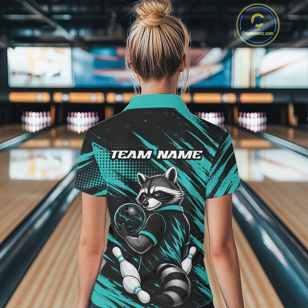 A woman viewed from behind wearing a short-sleeve bowling shirt with a raccoon graphic and 'TEAM NAME' text, standing in a bowling alley. The shirt has a black and teal design with a raccoon illustration holding a bowling ball.