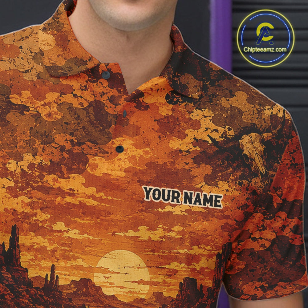 A close-up of a man wearing a short-sleeve polo shirt with a desert sunset print in orange, brown, and yellow. The shirt has a custom placeholder text 'YOUR NAME' on the chest and a visible 'Chapteeamz.