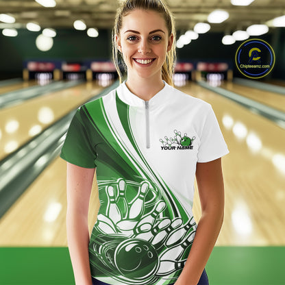 Front view of a female model in a white and green bowling quarter zip with flowing curve graphics and a bowling ball crashing into pins motif at the bowling lane.