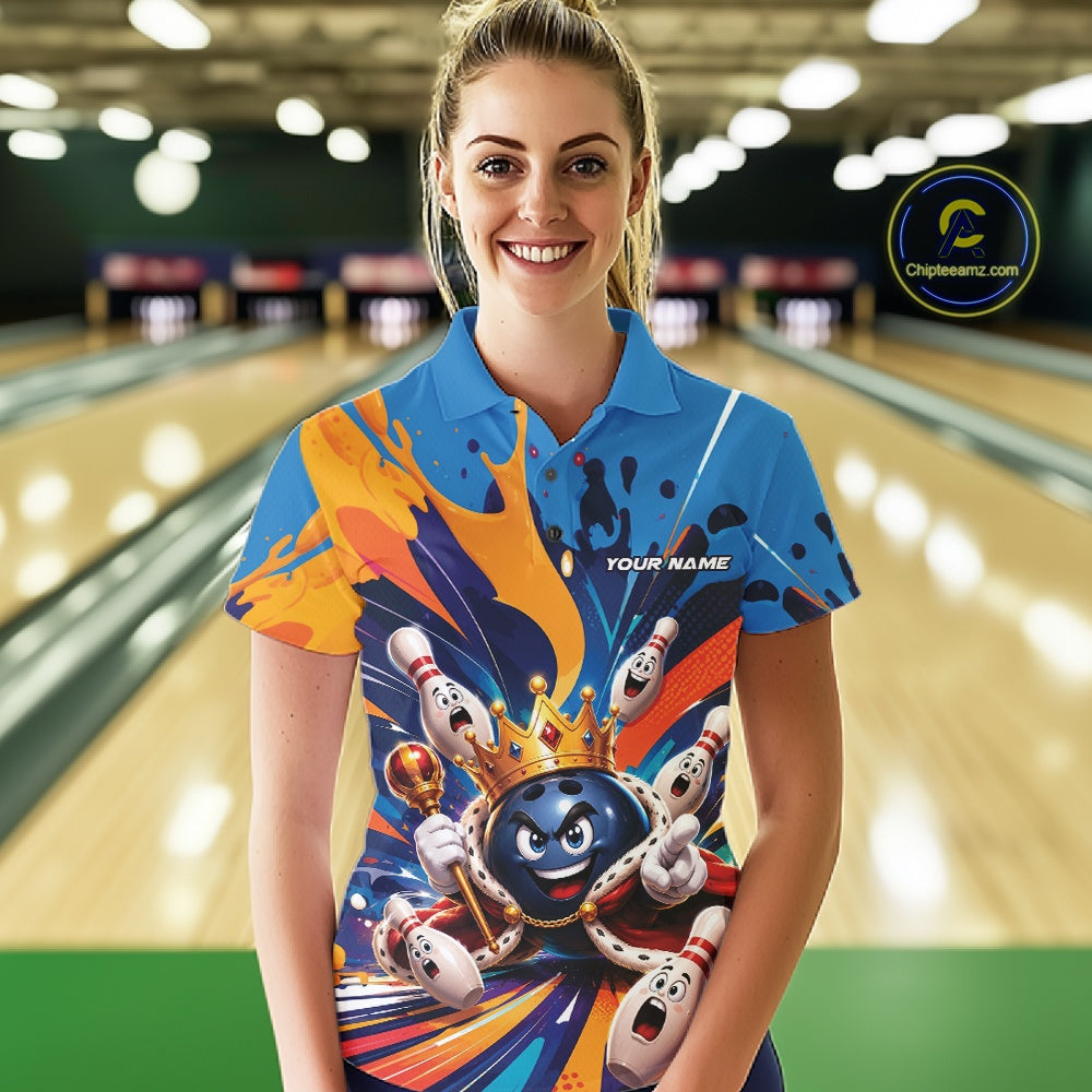 Front view of a female model wearing a bowling polo shirt featuring a crowned cartoon bowling ball holding a royal scepter with cheering animated pins and colorful paint splashes in a bowling lane.