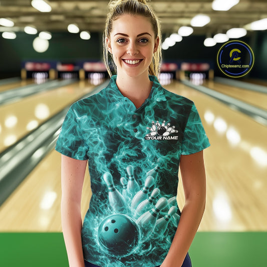 Female model in a bowling center wearing a polo with turquoise blue bowling ball artwork and blazing flames.