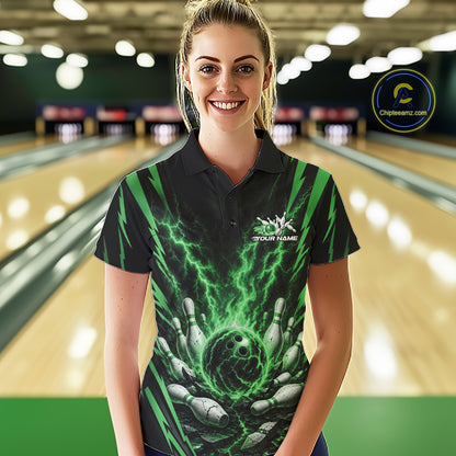 A woman wearing a custom black and green bowling-themed polo shirt with a lightning bolt and bowling hand graphic, standing in front of a blurred bowling alley background.