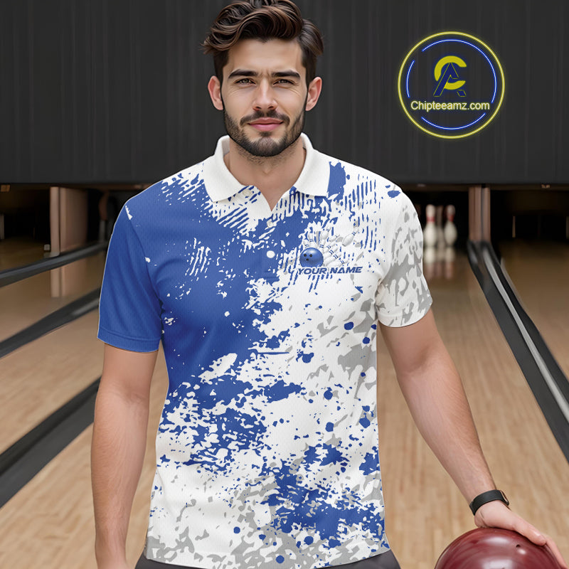 Front view of a male model in a bowling lane wearing a blue and white splatter polo shirt with minimalist bowling-inspired graphics.