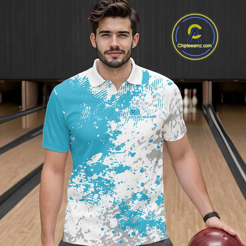 Front view of a male model in a bowling lane wearing a teal blue and white splatter polo shirt with dynamic sporty bowling visuals.