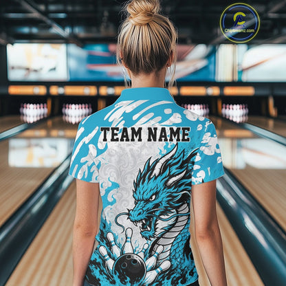 Person wearing a blue bowling shirt with a dragon design and 'TEAM NAME' text in a bowling alley.