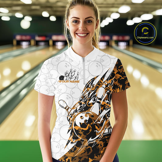 Female model wearing a white bowling quarter-zip shirt at the lane with orange camo bowling graphics and subtle bowling ball patterns.