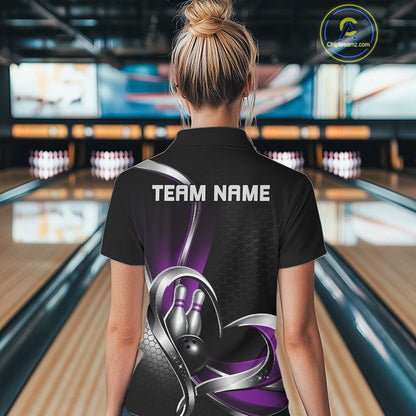Back view of a female model in a bowling venue wearing a black and purple quarter zip shirt with honeycomb accents and a heart-shaped bowling ball and pins design.
