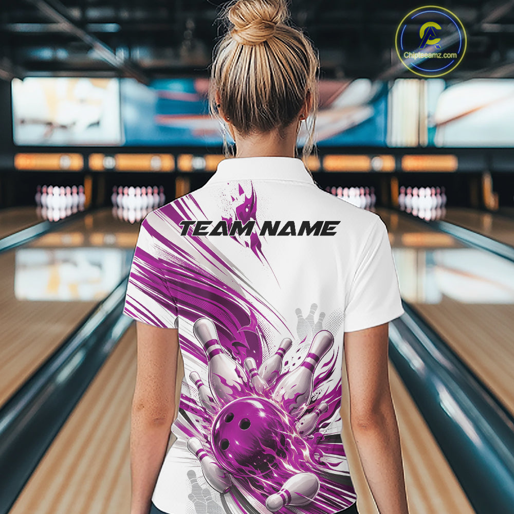 A woman viewed from behind wearing a white short-sleeve bowling shirt with a large purple and white bowling graphic and the text 'TEAM NAME' printed across the upper back. The background shows a blurred bowling alley with lanes and pins.