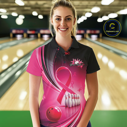 Female model in a black and pink bowling polo with breast cancer awareness ribbons and bowling artwork, front view inside a bowling alley