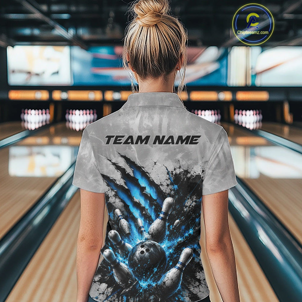 Back view of a female model wearing a gray bowling polo shirt with a dramatic blue bowling ball and pins graphic accented by claw-mark artwork in a bowling lane.
