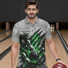 Load image into Gallery viewer, Front view of a male model wearing a gray bowling polo shirt with a dramatic green bowling ball striking pins graphic accented by claw-mark artwork in a bowling lane.