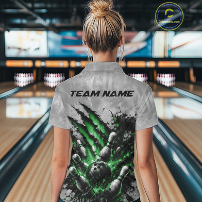 Back view of a female model wearing a gray bowling polo shirt featuring a dramatic green bowling ball and pins graphic with claw-mark artwork in a bowling lane.