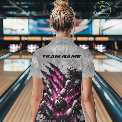 Back view of a female model wearing a gray bowling polo shirt showcasing a dramatic pink bowling ball and pins graphic with claw-mark artwork at a bowling lane.
