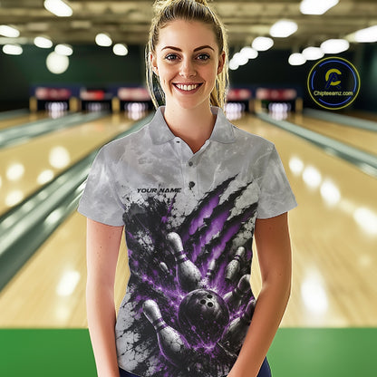 Front view of a female model wearing a gray bowling polo shirt featuring a dramatic purple bowling ball and pins graphic with claw-mark artwork in a bowling lane.
