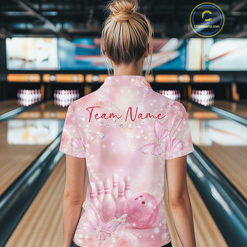 Back view of a female model at a bowling lane wearing a quarter-zip bowling shirt decorated with glitter butterflies, roses, and bowling-themed graphics.