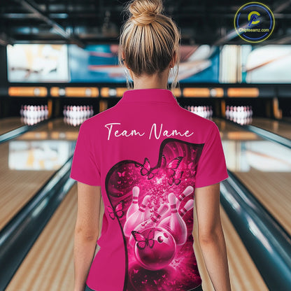Back view of a female model wearing a pink bowling quarter zip with butterfly artwork and bowling graphics at the bowling lane