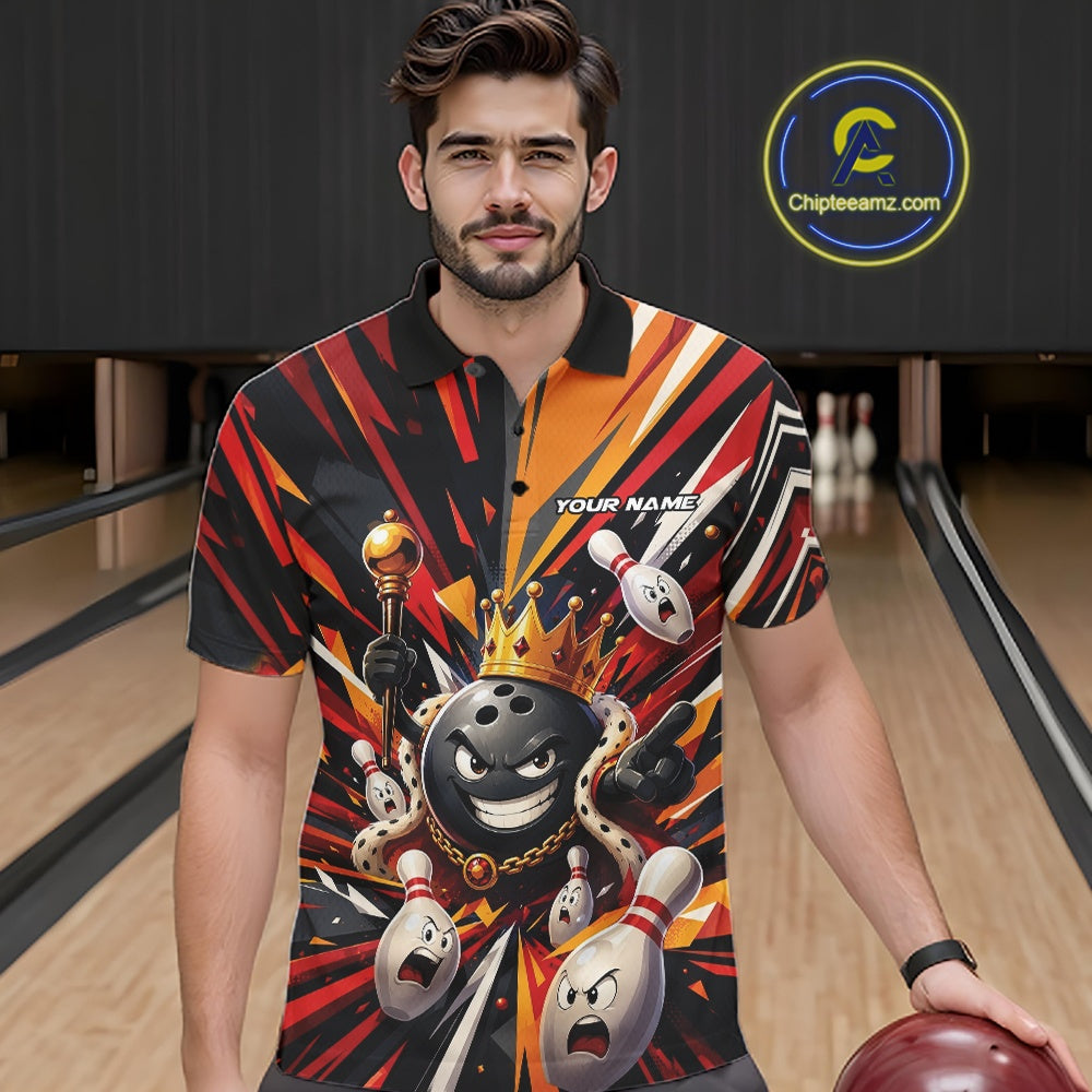 Front view of a male model wearing a black, red, and orange bowling polo shirt featuring a crowned cartoon bowling ball with a royal scepter leading animated bowling pins through radiant bursts of color at a bowling lane.