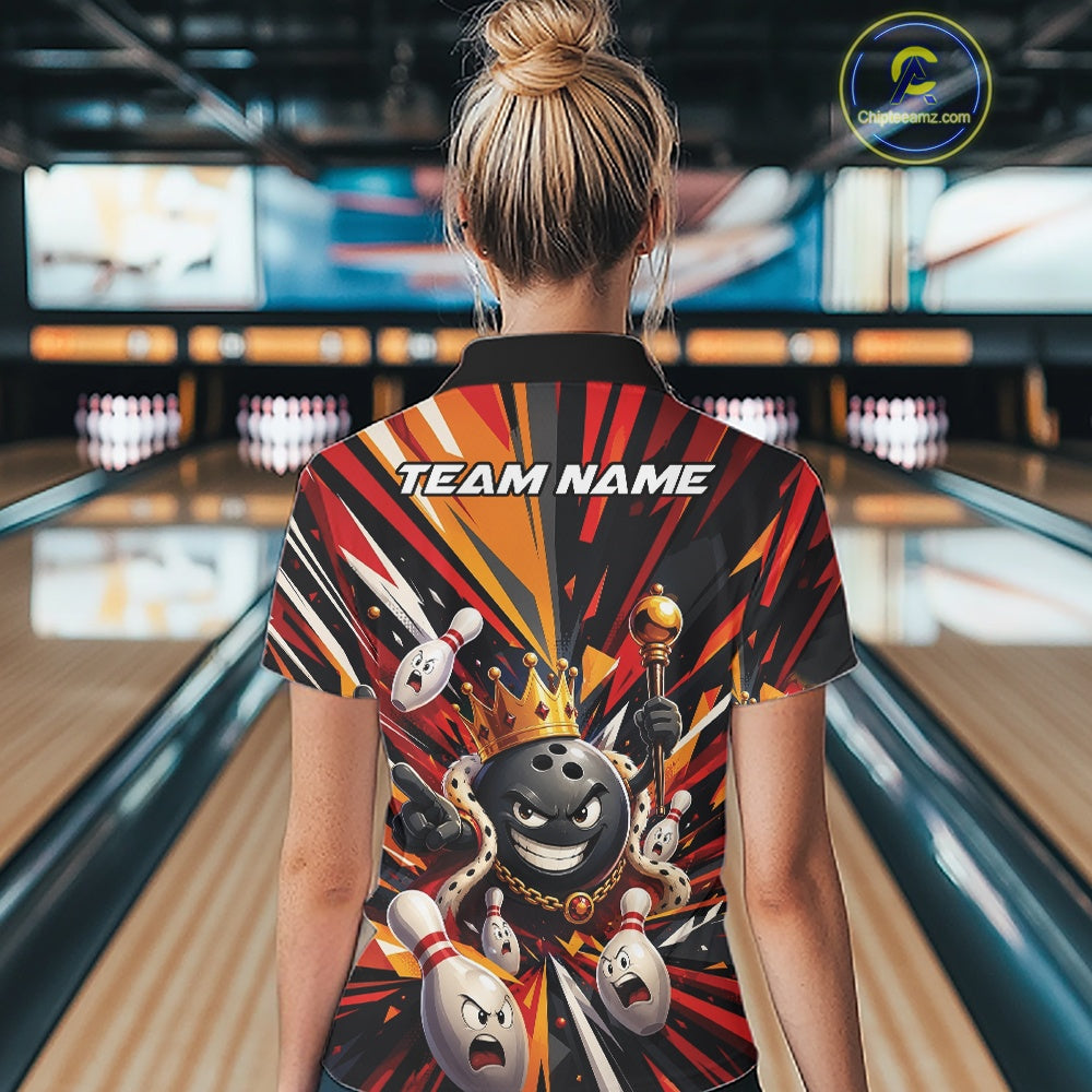Back view of a female model wearing a black, red, and orange bowling polo shirt showcasing a crowned cartoon bowling ball holding a royal scepter with animated bowling pins and colorful burst artwork in a bowling lane.