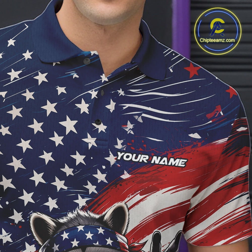 Close-up of the left chest on a bowling polo shirt featuring a patriotic raccoon, a red, white, and blue bowling ball striking pins, and a flowing American flag design.