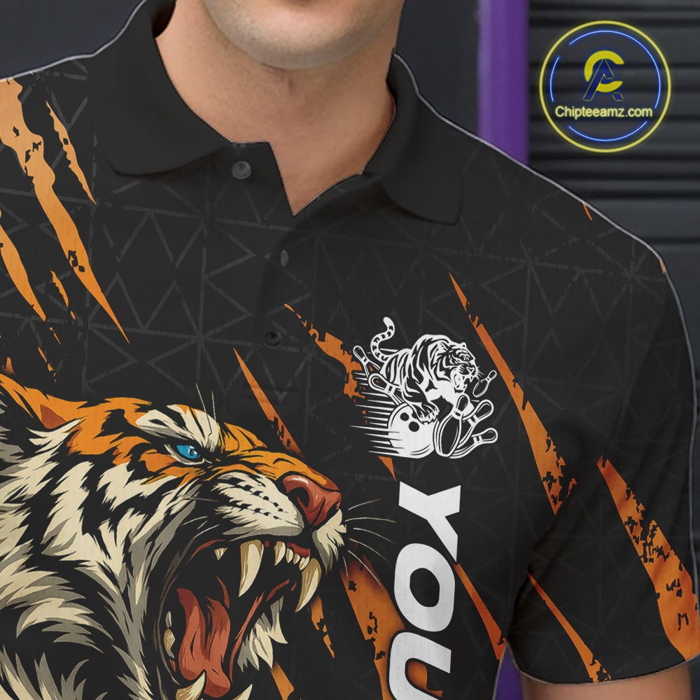 Close-up view of the left chest on a black and yellow bowling polo shirt featuring a roaring tiger holding a yellow bowling ball with orange claw-stripe artwork and a geometric background pattern.