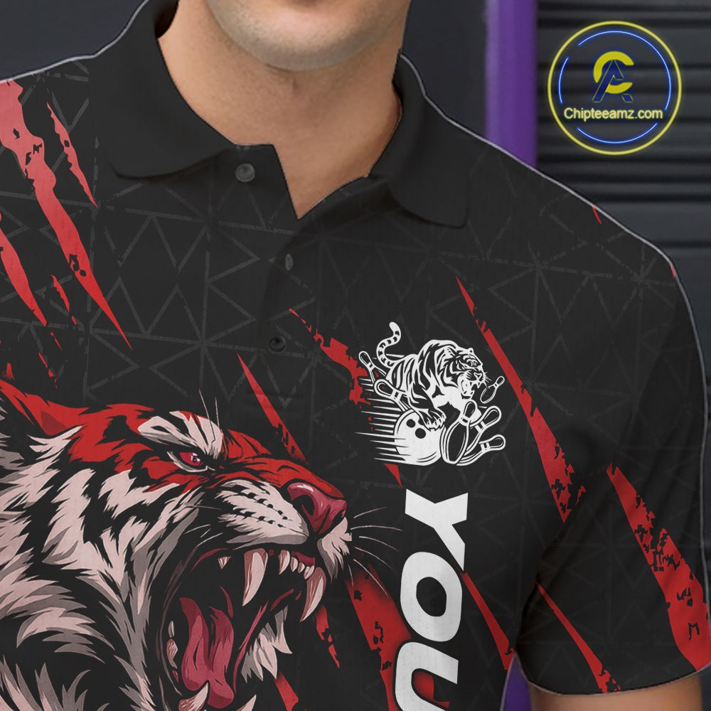Close-up view of the left chest on a black and red bowling polo shirt displaying a roaring tiger holding a red bowling ball with matching red claw-stripe artwork and a geometric background pattern.
