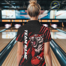Load image into Gallery viewer, Back view of a female model wearing a black and red bowling quarter-zip shirt at a bowling lane, displaying a roaring tiger holding a red bowling ball with matching claw-stripe artwork and a geometric background pattern.