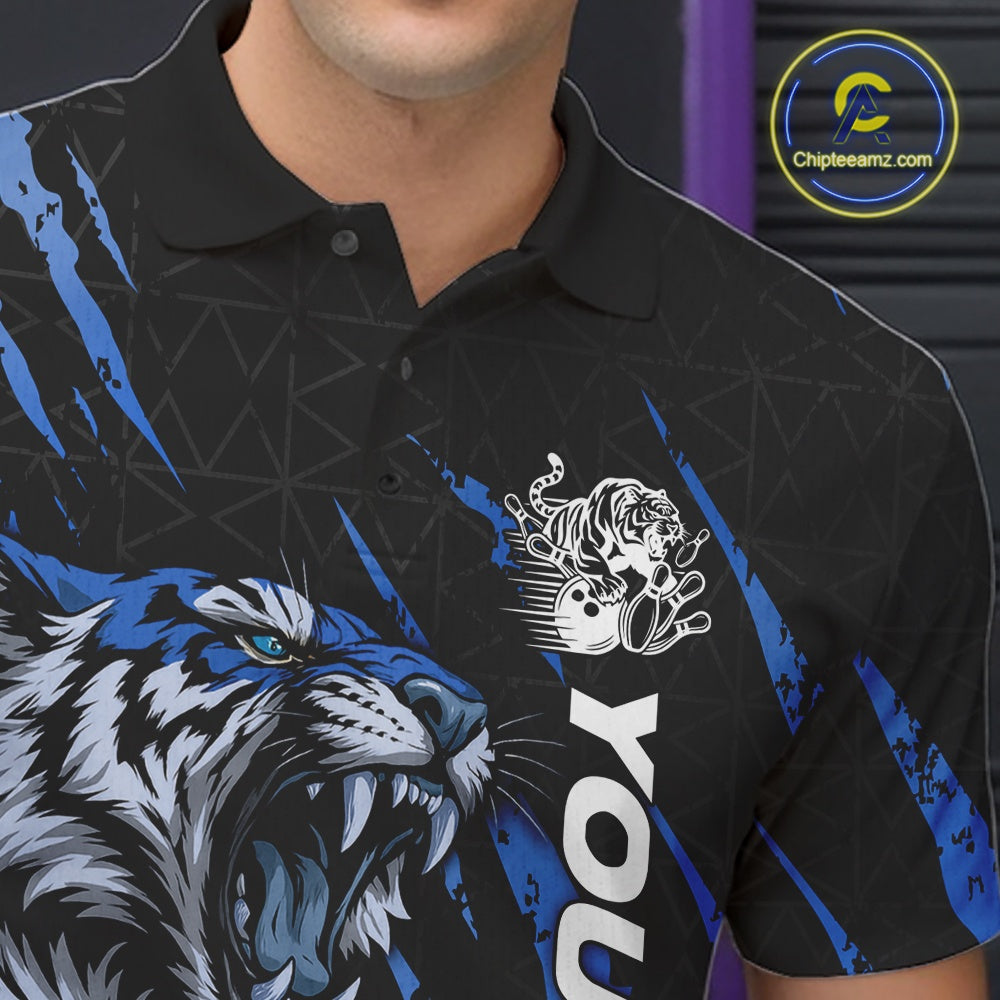 Close-up view of the left chest on a black and mid blue bowling polo shirt featuring a roaring tiger holding a mid blue bowling ball with coordinated claw-stripe graphics and a geometric background pattern.