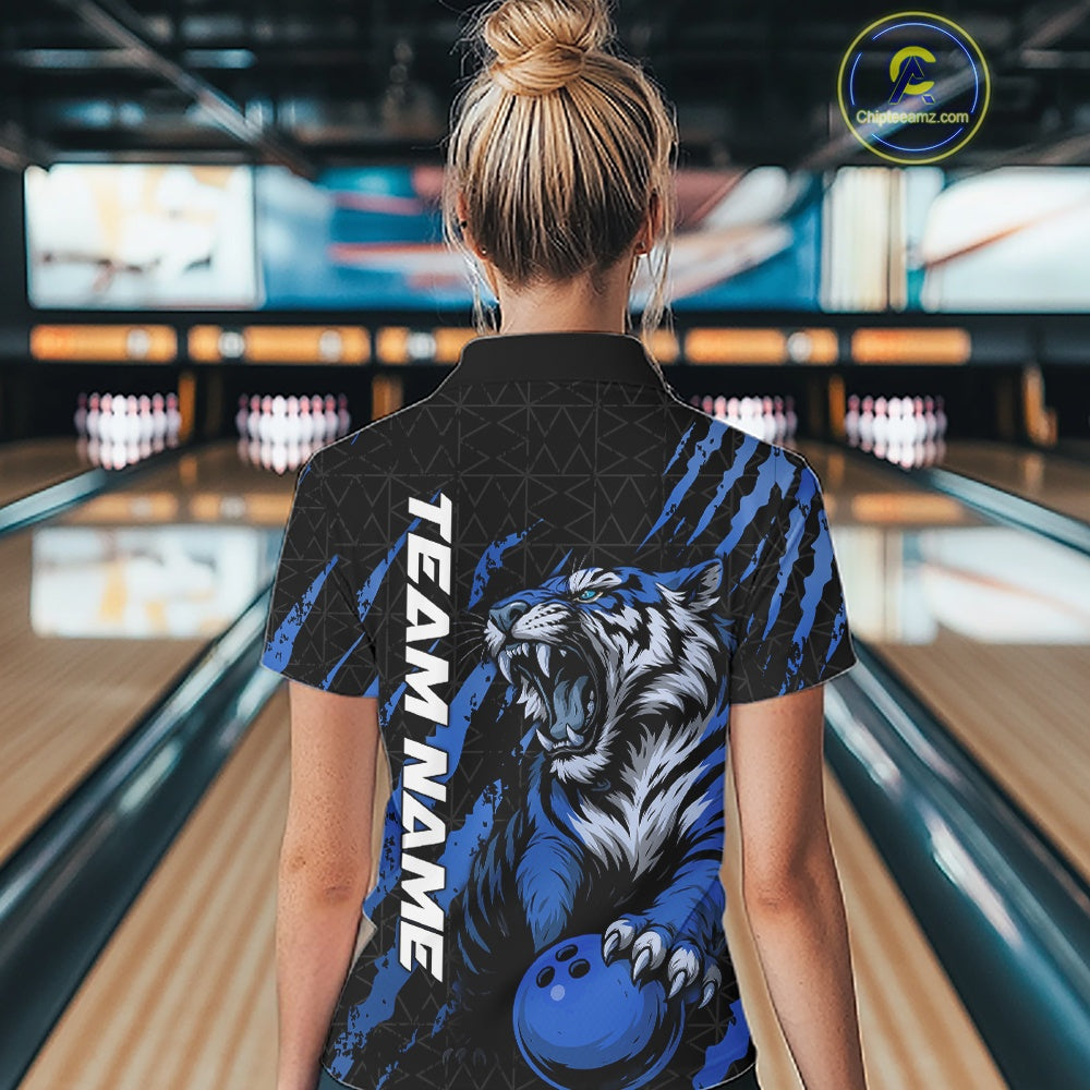 Back view of a female model wearing a black and mid blue bowling polo shirt in a bowling lane, featuring a roaring tiger holding a mid blue bowling ball with coordinated claw-stripe graphics and a geometric background pattern.
