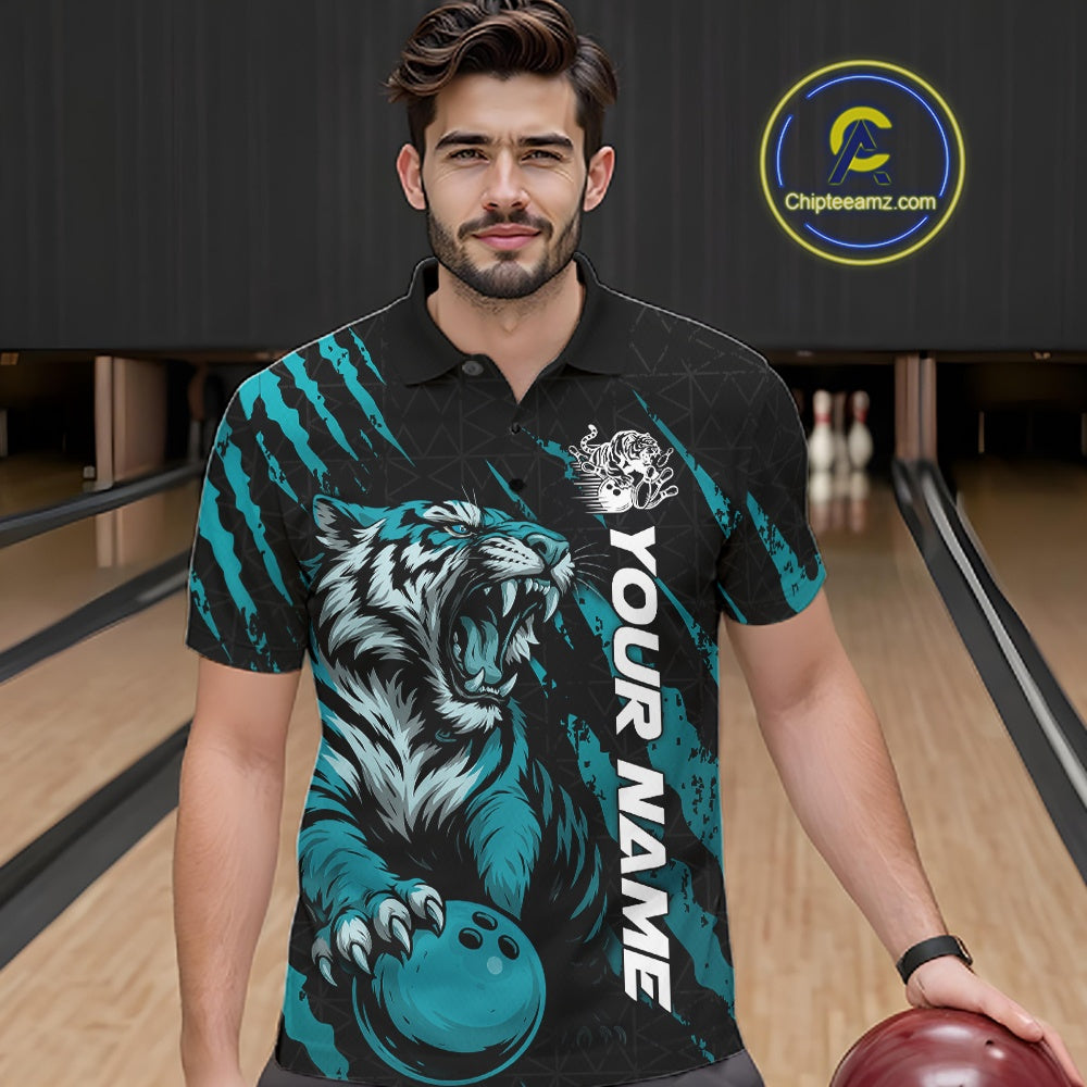 Front view of a male model at a bowling lane wearing a black and teal blue bowling polo shirt featuring a roaring tiger holding a teal blue bowling ball with matching claw-stripe graphics and a geometric background pattern.