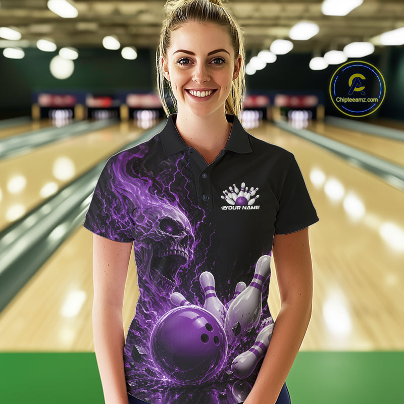 Front view of a female model in a bowling alley wearing a black bowling polo with a purple flaming skull, lightning, bowling pins, and a custom name.
