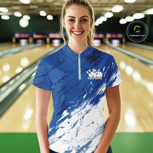 Load image into Gallery viewer, Front view of a female bowler in a bowling alley wearing a white and blue bowling quarter-zip shirt with a dynamic splatter jersey pattern
