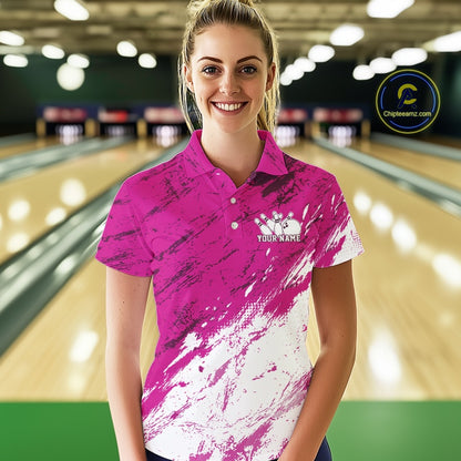 Woman wearing a pink and white bowling shirt with a logo in a bowling alley.