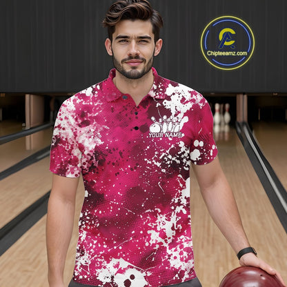 Front view of a female model in a bowling alley wearing a bowling polo shirt featuring a white paint splatter design on an orange shirt.
