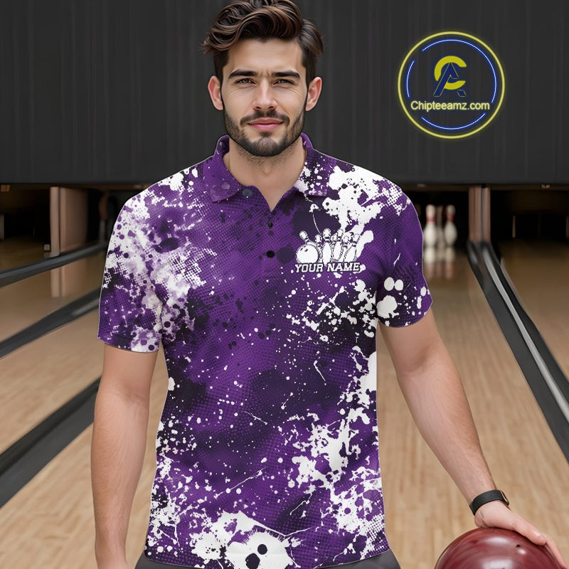 Front view of a male model in a bowling alley wearing a purple bowling polo shirt featuring a white paint splatter sportswear design.
