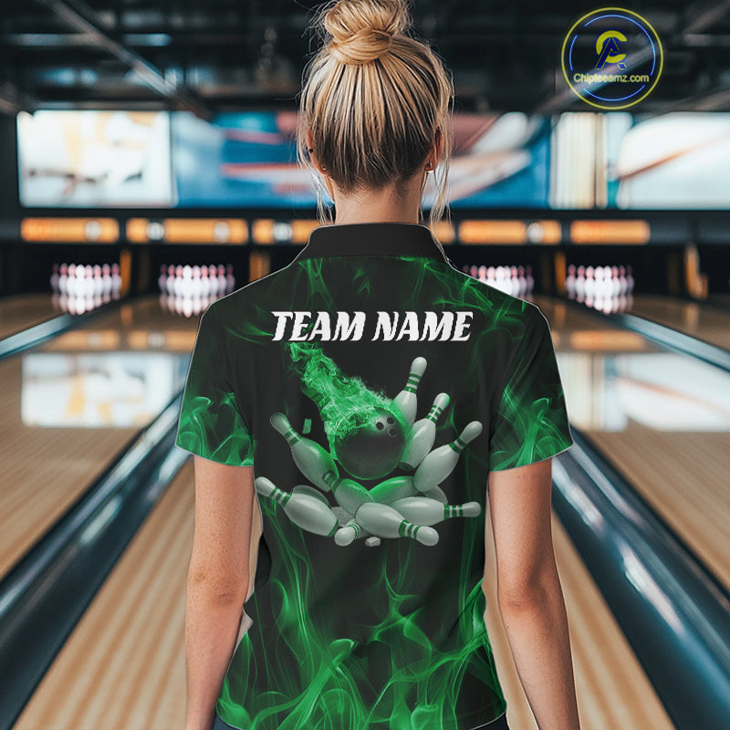 Back view of a female model in a bowling venue wearing a black and green quarter-zip shirt showcasing a bowling ball and scattered pin graphics.