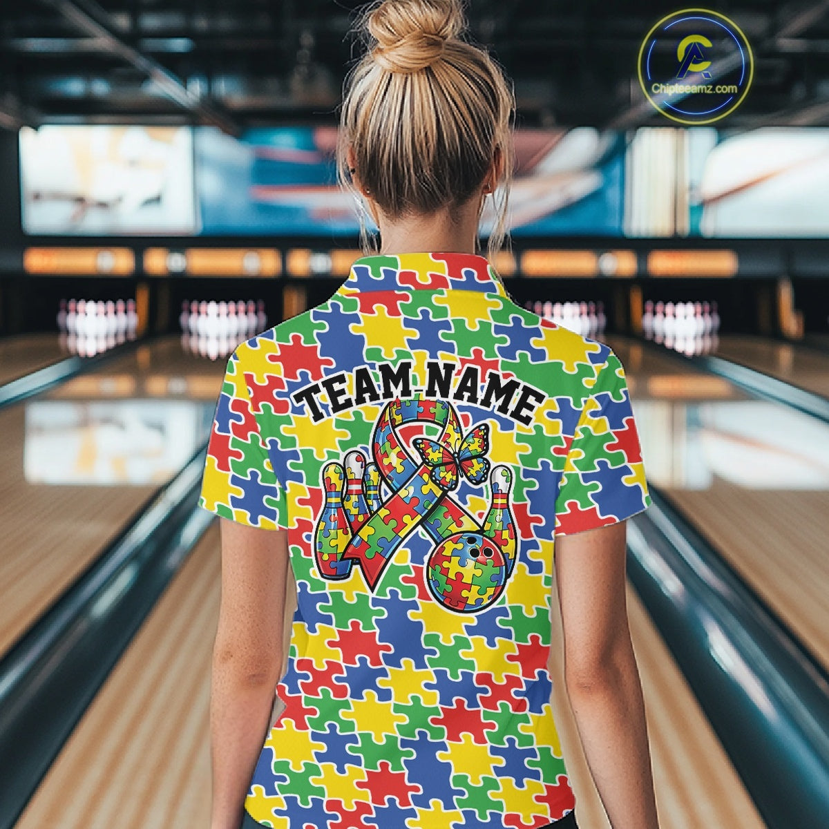 Female model in a bowling alley, back view of colorful polo shirt featuring seamless multicolor puzzle piece pattern across fabric