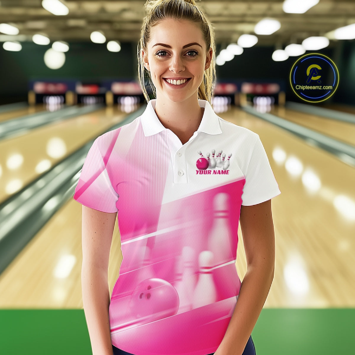 Front view female model at the bowling lane wearing a white and pink bowling polo shirt with bowling ball and pins geometric artwork.