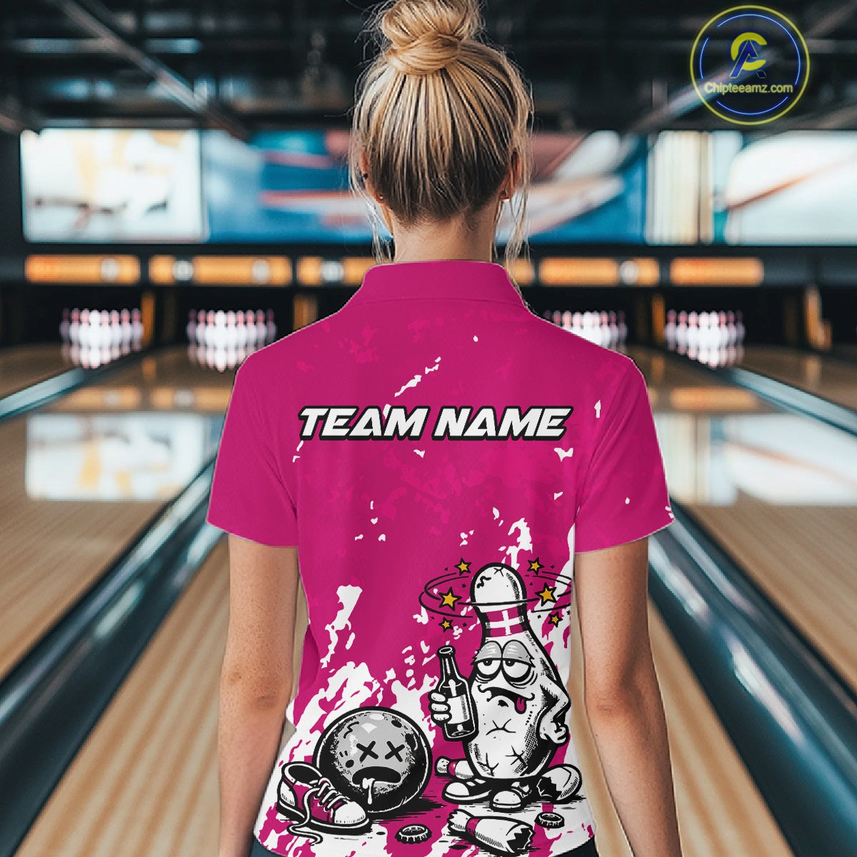 Back view of a female bowler wearing a pink and white polo shirt, humorous splatter drunk bowling pin illustration holding beer bottle and bowling ball.