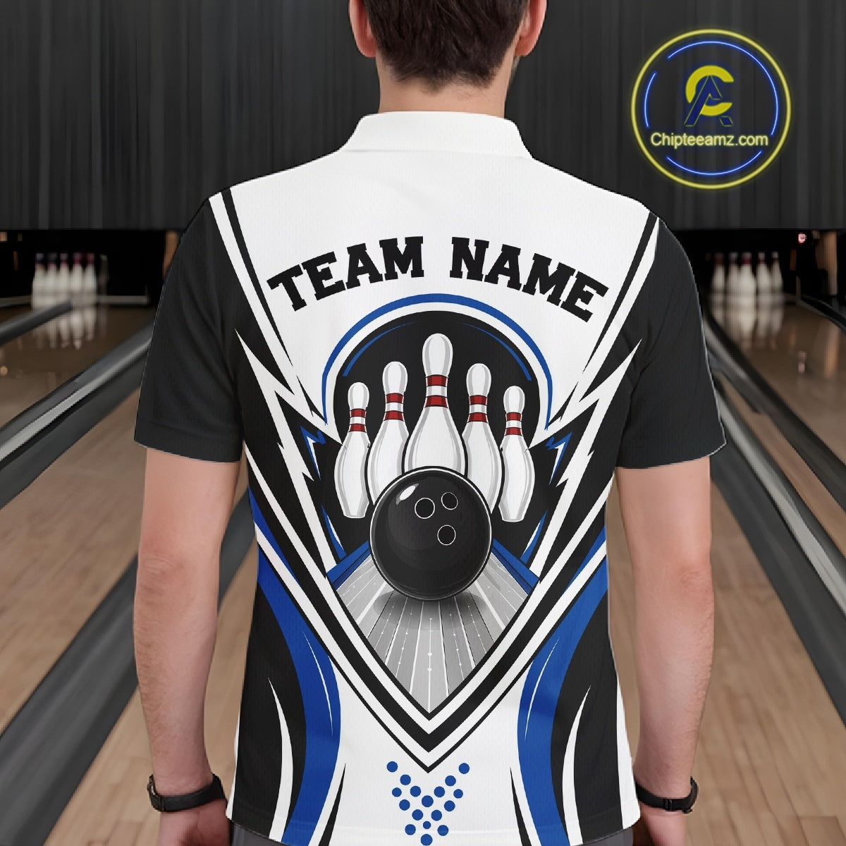 Back view of a male model wearing a white, black, and blue bowling polo shirt with bowling ball and pins graphics at a bowling lane.