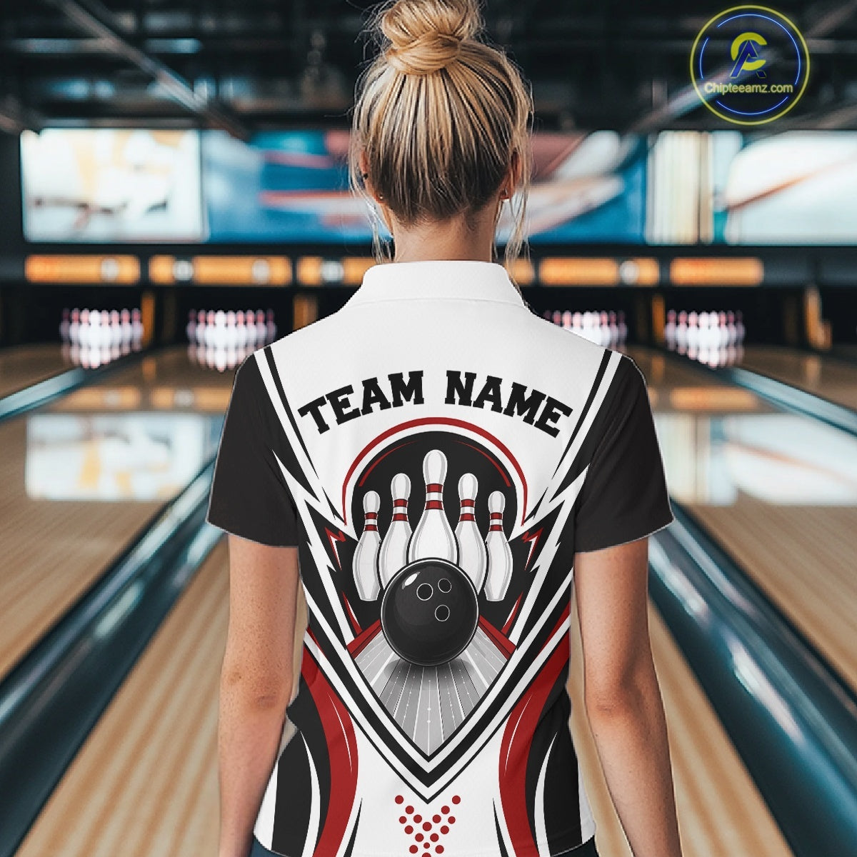 Back view of a female model in a bowling venue wearing a white, black, and red bowling polo shirt featuring bowling ball and pins graphics.