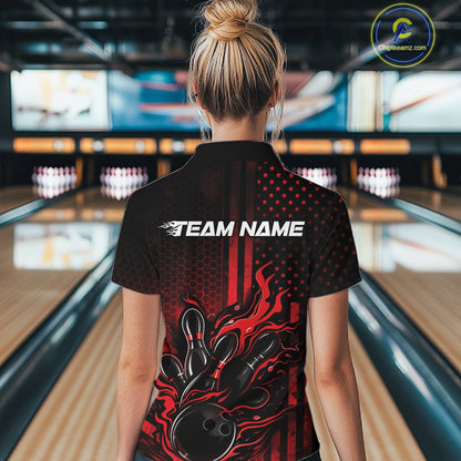 Back view of a female model in a bowling alley wearing a black and red quarter-zip shirt showcasing a flaming bowling ball hitting the pins.