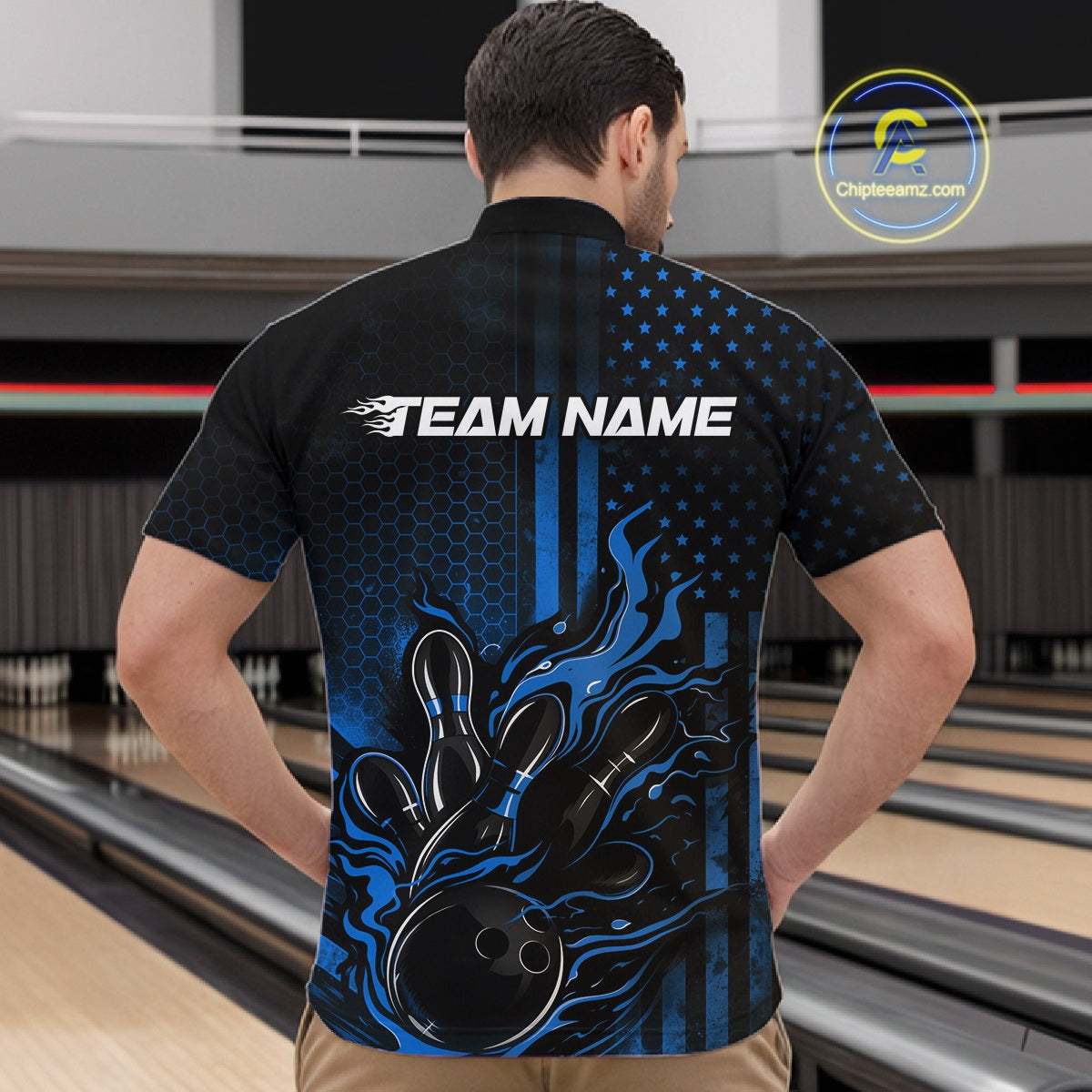 Front view of a male model in a bowling venue wearing a black and blue quarter-zip shirt featuring a bowling action scene with flame effects.