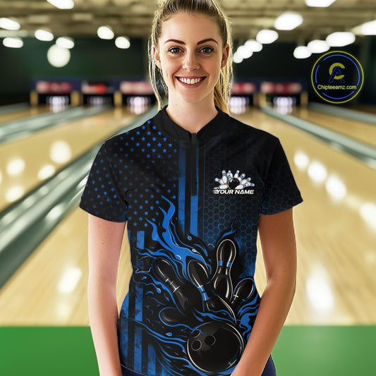 Female model at a bowling lane wearing a black and blue bowling quarter-zip shirt with fiery bowling action artwork and patriotic details.