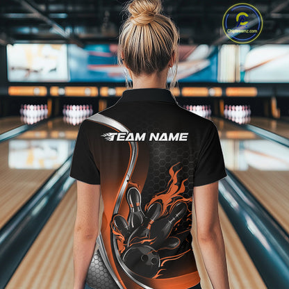 Female model back view at bowling lane wearing black and orange quarter zip shirt featuring flaming bowling ball striking pins artwork