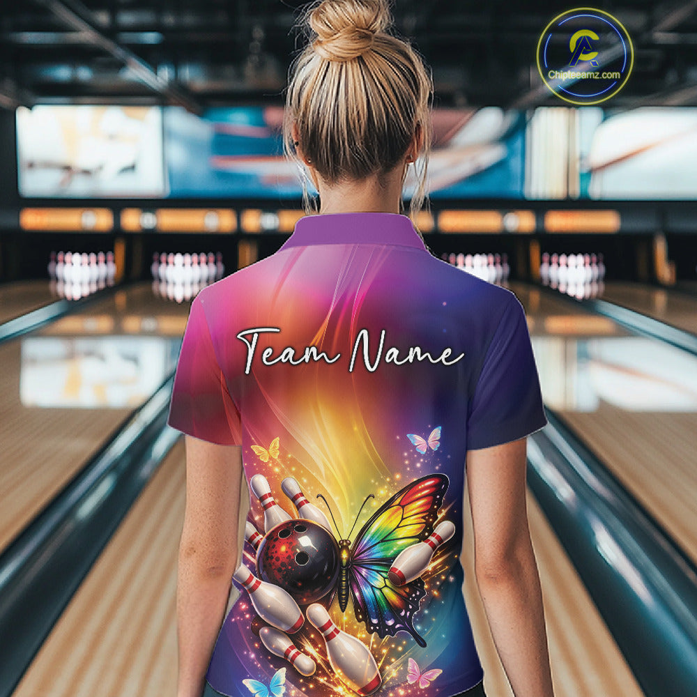 Back view of a female model in a bowling alley wearing a bowling polo shirt showcasing a rainbow butterfly beside a bowling ball and bowling pins.