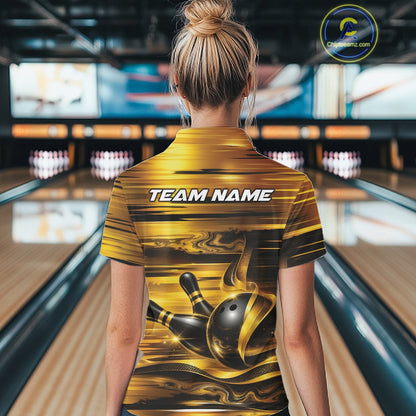Back view of a female model inside a bowling center wearing a bowling polo shirt with glossy gold and black bowling ball and pins artwork.